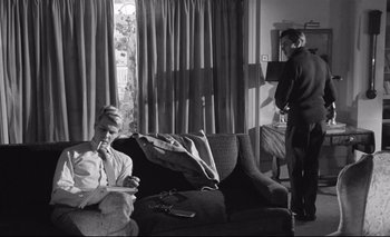 Movie still from “The Servant” (1963), directed by Joseph Losey – A woman sitting on a couch in a living room; Medium shot, Low angle