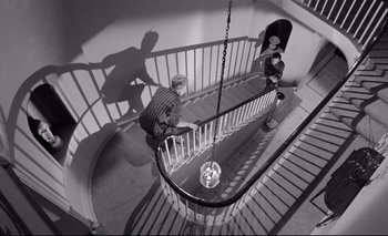 Movie still from “The Servant” (1963), directed by Joseph Losey – Three people are walking down a spiral staircase; Wide shot, High angle