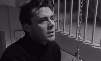 Movie still from “The Servant” (1963), directed by Joseph Losey – Black and white photograph of a man in front of a fence; Close Up shot, Low angle