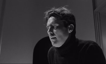 Movie still from “The Servant” (1963), directed by Joseph Losey – Black and white photograph of a man in a sweater looking to his left; Close Up shot, Low angle
