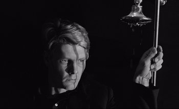 Movie still from “The Servant” (1963), directed by Joseph Losey – A black and white photo of a man in a dark room; Close Up shot, Low angle