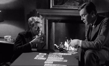 Movie still from “The Servant” (1963), directed by Joseph Losey – A man and a woman sitting at a table playing cards; Medium shot, High angle