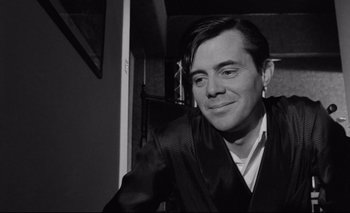 Movie still from “The Servant” (1963), directed by Joseph Losey – Black and white photograph of a man smiling; Close Up shot, Low angle