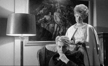 Movie still from “The Servant” (1963), directed by Joseph Losey – An older woman and a young man in a chair; Medium shot, Low angle