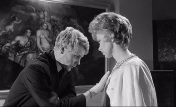 Movie still from “The Servant” (1963), directed by Joseph Losey – A man and a woman are touching each other's hands; Medium shot, Low angle