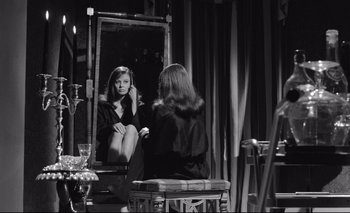 Movie still from “The Servant” (1963), directed by Joseph Losey – A woman sitting in front of a mirror in front of a table; Medium shot, Over the shoulder angle