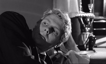 Movie still from “The Servant” (1963), directed by Joseph Losey – Black and white photograph of a man with a tie; Close Up shot, Low angle