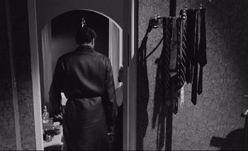 Movie still from “The Servant” (1963), directed by Joseph Losey – A black and white photo of a man in a suit and tie; Medium shot, Over the shoulder angle