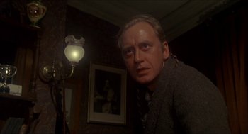 Movie still from “The Seven-Per-Cent Solution” (1976), directed by Herbert Ross – A man standing in front of a lamp in a dark room; Close Up shot, Low angle