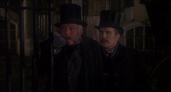 Movie still from “The Seven-Per-Cent Solution” (1976), directed by Herbert Ross – Two men in top hats and coats standing next to each other; Medium shot, Low angle