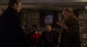 Movie still from “The Seven-Per-Cent Solution” (1976), directed by Herbert Ross – A man sitting in a chair next to two other men; Medium shot, Over the shoulder angle