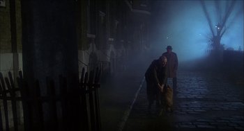 Movie still from “The Seven-Per-Cent Solution” (1976), directed by Herbert Ross – Two men are standing on the sidewalk in the fog; Wide shot, Over the shoulder angle