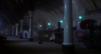 Movie still from “The Seven-Per-Cent Solution” (1976), directed by Herbert Ross – A man standing next to a train in a train station; Extreme Wide shot, Low angle
