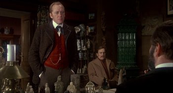 Movie still from “The Seven-Per-Cent Solution” (1976), directed by Herbert Ross – A man standing next to a man sitting in a chair; Medium shot, Over the shoulder angle