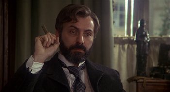 Movie still from “The Seven-Per-Cent Solution” (1976), directed by Herbert Ross – A man with a beard and a suit and tie holding a cigar; Close Up shot, Over the shoulder angle