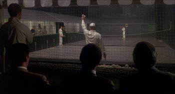 Movie still from “The Seven-Per-Cent Solution” (1976), directed by Herbert Ross – A man in a baseball uniform holding a bat in front of an audience; Wide shot, Low angle