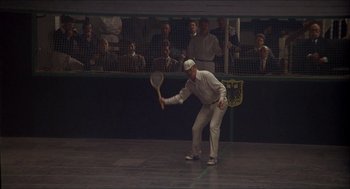 Movie still from “The Seven-Per-Cent Solution” (1976), directed by Herbert Ross – A man holding a tennis racquet on a tennis court; Wide shot, Low angle