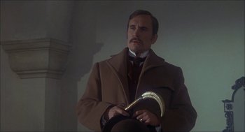 Movie still from “The Seven-Per-Cent Solution” (1976), directed by Herbert Ross – A man in a brown coat holding a gold object; Close Up shot, Low angle