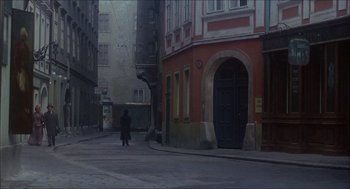 Movie still from “The Seven-Per-Cent Solution” (1976), directed by Herbert Ross – A person walking down a street near a building; Wide shot, High angle