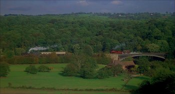 Movie still from “The Seven-Per-Cent Solution” (1976), directed by Herbert Ross – A train traveling over a lush green hillside; Extreme Wide shot, High angle