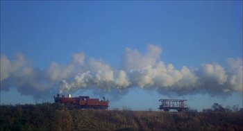 Movie still from “The Seven-Per-Cent Solution” (1976), directed by Herbert Ross – A train traveling down the tracks near a forest; Extreme Wide shot, Low angle