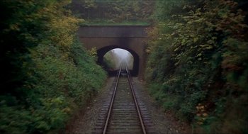 Movie still from “The Seven-Per-Cent Solution” (1976), directed by Herbert Ross – A train track going through a tunnel in the middle of a forest; Extreme Wide shot, High angle