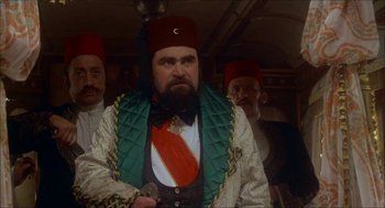 Movie still from “The Seven-Per-Cent Solution” (1976), directed by Herbert Ross – A bearded man in a red hat and a green vest; Medium shot, Low angle