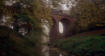 Movie still from “The Seven-Per-Cent Solution” (1976), directed by Herbert Ross – A train traveling over a bridge next to a river; Extreme Wide shot, Low angle
