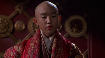Movie still from “The Shadow” (1994), directed by Russell Mulcahy – A man with a bald head wearing a red robe; Close Up shot, Low angle