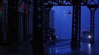 Movie still from “The Shadow” (1994), directed by Russell Mulcahy – A car is driving under an overpass at night; Extreme Wide shot, High angle