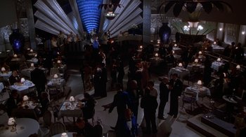 Movie still from “The Shadow” (1994), directed by Russell Mulcahy – A group of people standing in a room with lights; Extreme Wide shot, High angle