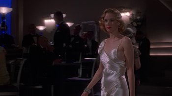 Movie still from “The Shadow” (1994), directed by Russell Mulcahy – A woman in a white dress is walking in a room; Medium shot, Low angle