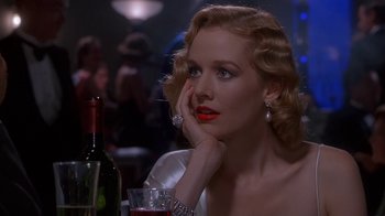 Movie still from “The Shadow” (1994), directed by Russell Mulcahy – A woman sitting in front of a wine glass; Close Up shot, Over the shoulder angle