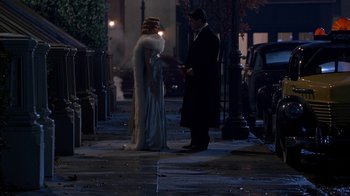 Movie still from “The Shadow” (1994), directed by Russell Mulcahy – A man and a woman standing on a sidewalk; Wide shot, High angle
