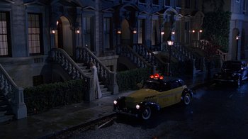 Movie still from “The Shadow” (1994), directed by Russell Mulcahy – A yellow car parked on the side of the street; Wide shot, High angle