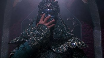 Movie still from “The Shadow” (1994), directed by Russell Mulcahy – A person wearing a mask and holding his hand up to his face; Close Up shot, Low angle