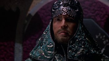 Movie still from “The Shadow” (1994), directed by Russell Mulcahy – A man with a beard wearing a green and silver headdress; Close Up shot, High angle