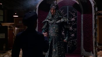 Movie still from “The Shadow” (1994), directed by Russell Mulcahy – A man dressed as a chinese emperor in a costume; Medium shot, Over the shoulder angle