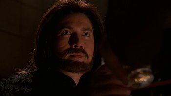Movie still from “The Shadow” (1994), directed by Russell Mulcahy – A man with long hair and a beard looking up; Close Up shot, Over the shoulder angle