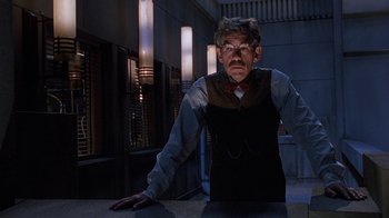 Movie still from “The Shadow” (1994), directed by Russell Mulcahy – An older man wearing glasses and a tie; Medium shot, Low angle