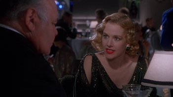 Movie still from “The Shadow” (1994), directed by Russell Mulcahy – A woman sitting at a dinner table talking to an older man; Close Up shot, Over the shoulder angle