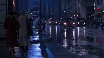 Movie still from “The Shadow” (1994), directed by Russell Mulcahy – A city street at night filled with lots of traffic; Wide shot, Over the shoulder angle