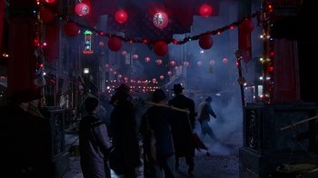 Movie still from “The Shadow” (1994), directed by Russell Mulcahy – A group of people walking down a street at night; Wide shot, High angle