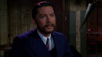 Movie still from “The Shadow” (1994), directed by Russell Mulcahy – A person wearing a suit and tie; Close Up shot, High angle