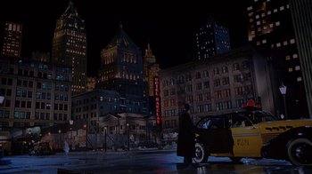 Movie still from “The Shadow” (1994), directed by Russell Mulcahy – A man in a black coat and a car in the dark; Extreme Wide shot, High angle