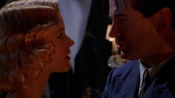 Movie still from “The Shadow” (1994), directed by Russell Mulcahy – A man and a woman face to face in front of a lamp; Close Up shot, Low angle