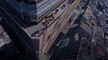 Movie still from “The Shadow” (1994), directed by Russell Mulcahy – An aerial view of a building with people sitting on it; Extreme Wide shot, Overhead angle