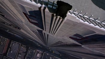 Movie still from “The Shadow” (1994), directed by Russell Mulcahy – A man riding a skateboard down the side of a building; Extreme Wide shot, Overhead angle