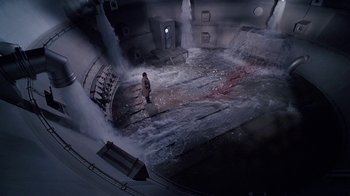 Movie still from “The Shadow” (1994), directed by Russell Mulcahy – A man standing in front of a large wave; Extreme Wide shot, High angle