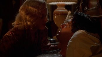 Movie still from “The Shadow” (1994), directed by Russell Mulcahy – A woman sitting next to a man on a couch; Close Up shot, High angle